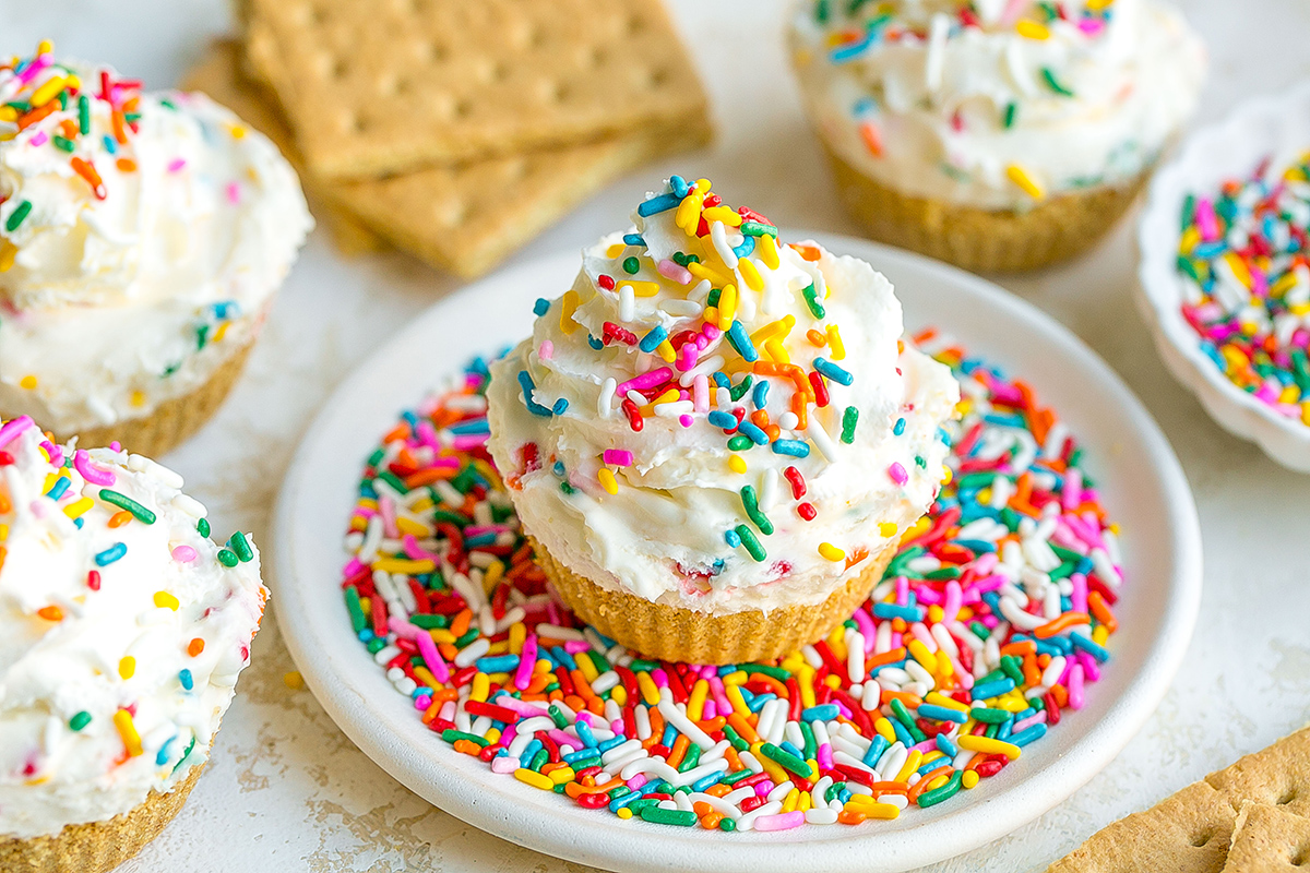 angled shot of funfetti cheesecake bite on plate of sprinkles