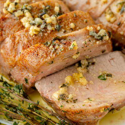 angled shot of sliced pork tenderloin medallions with garlic butter