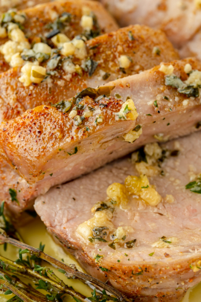 angled shot of sliced pork tenderloin medallions with garlic butter