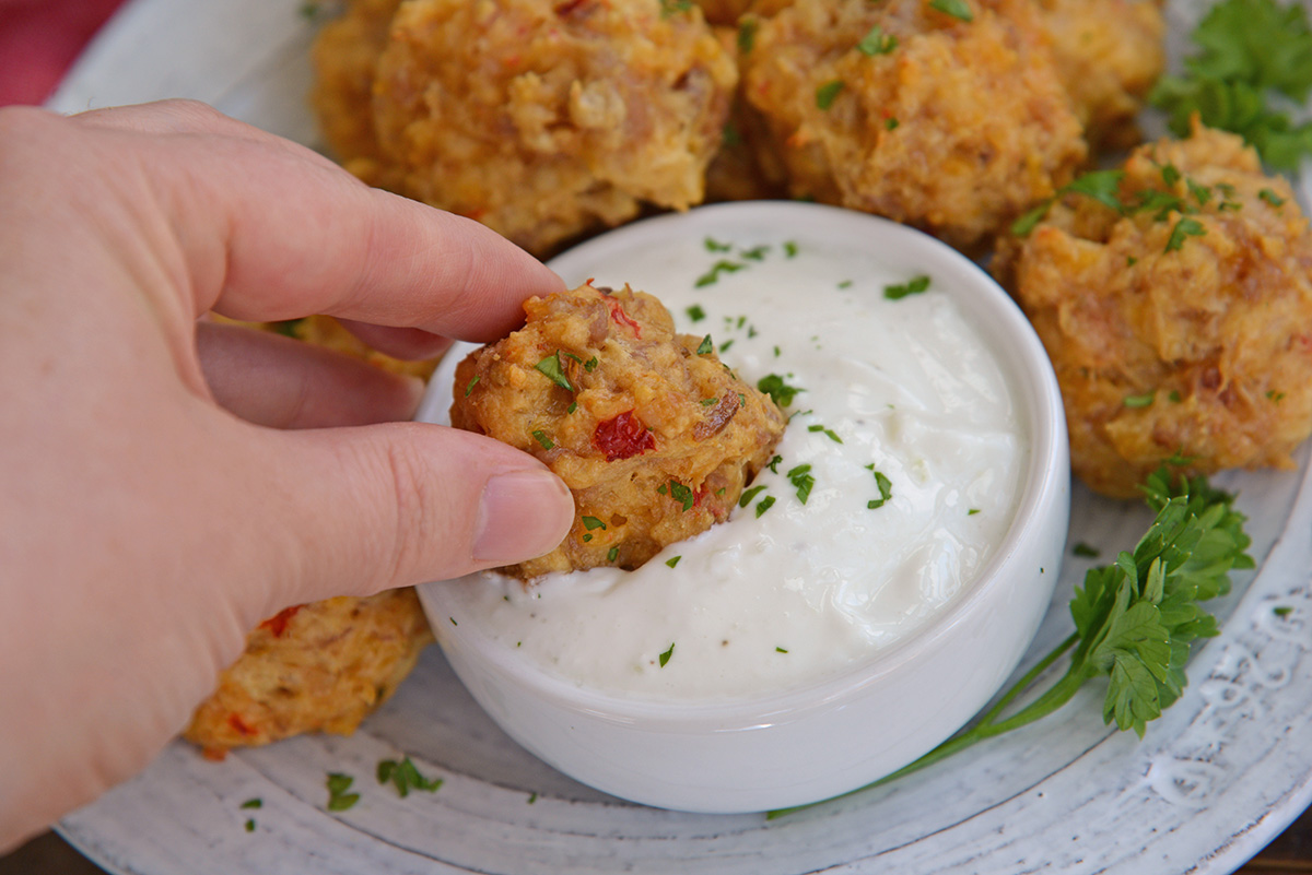 hand dipping sausage balls into sauce