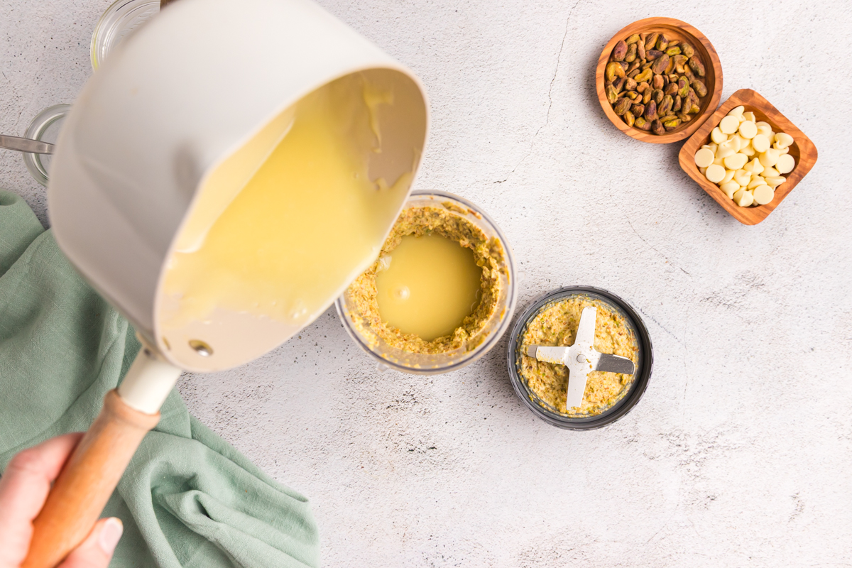 overhead shot of melted white chocolate pouring into crushed pistachios