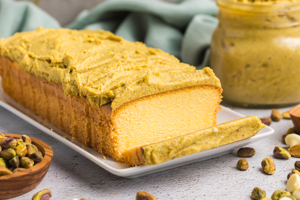 angled shot of sliced pound cake topped with pistachio cream