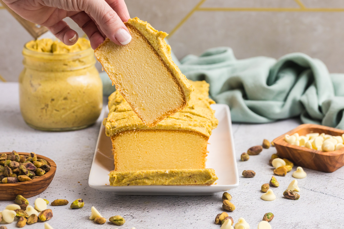 hand grabbing slice of pound cake topped with pistachio cream